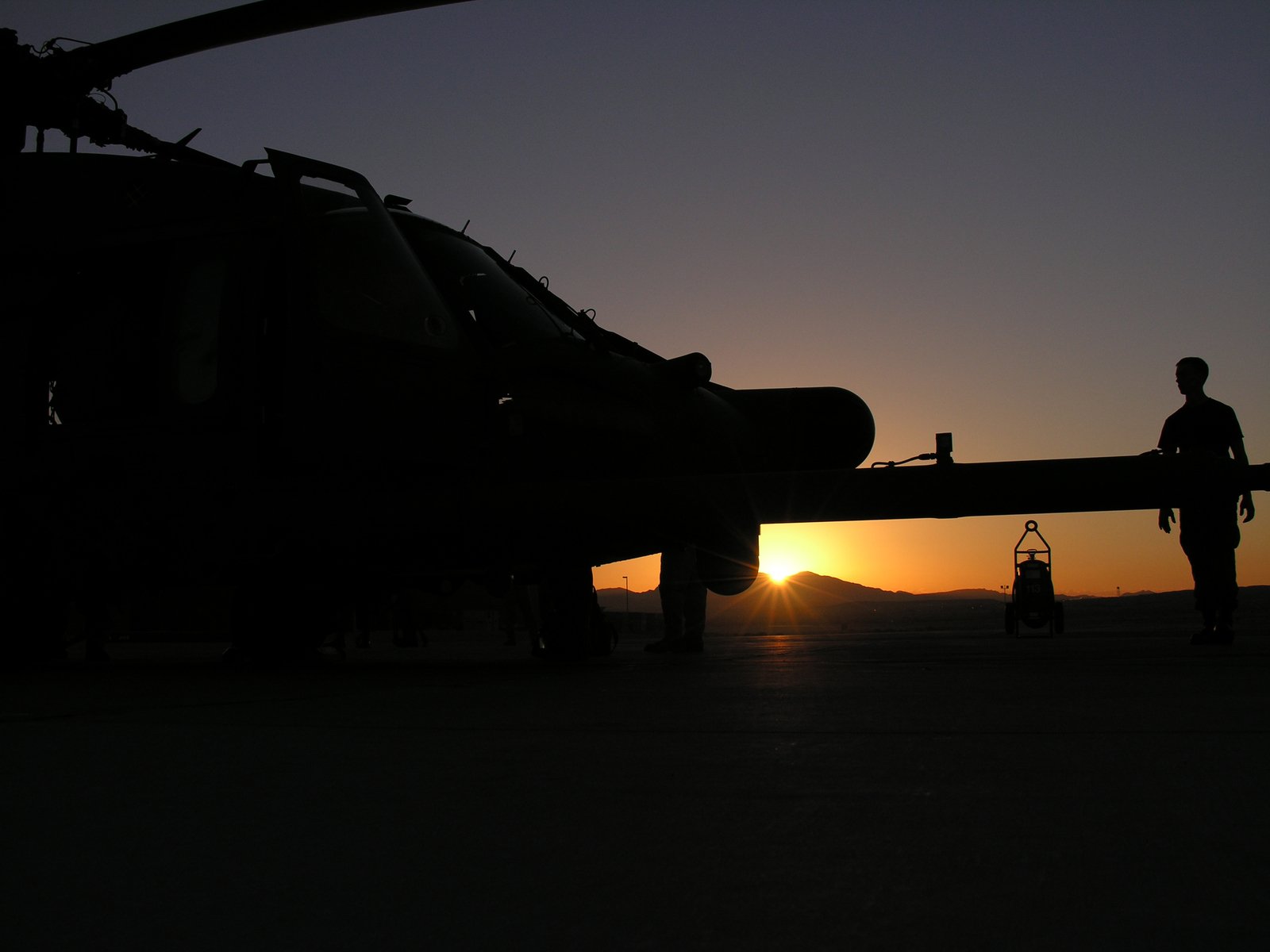 a person standing next to an aircraft at sunset