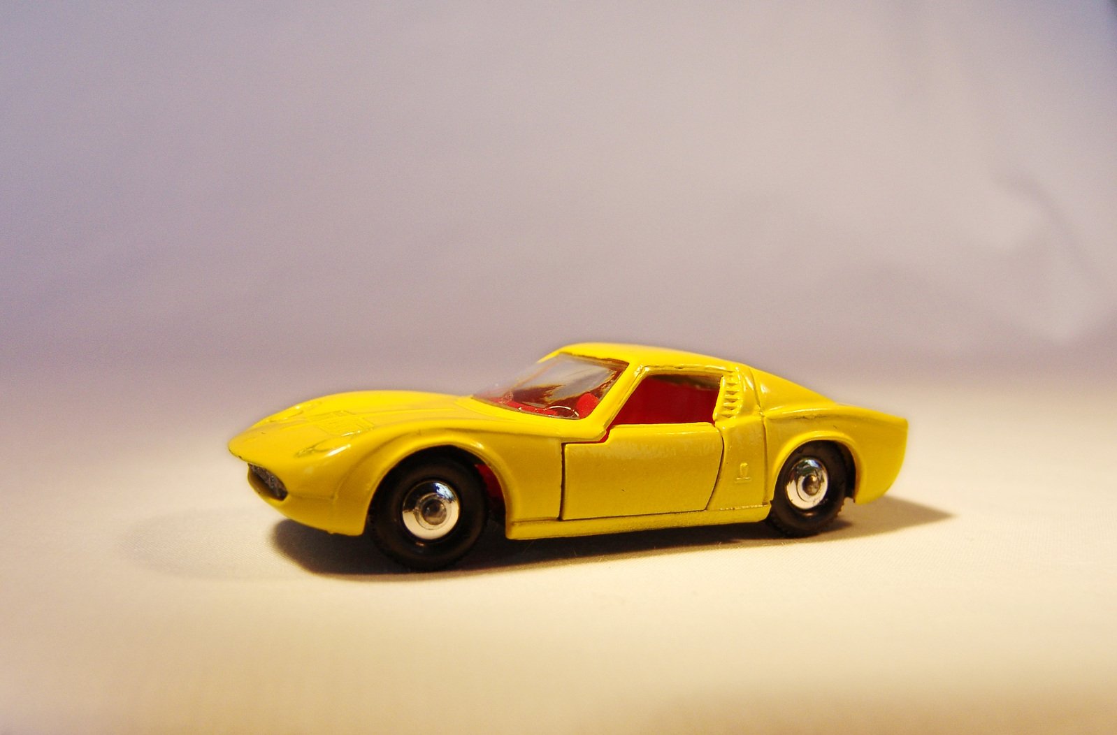 a model yellow sports car, in a studio setting