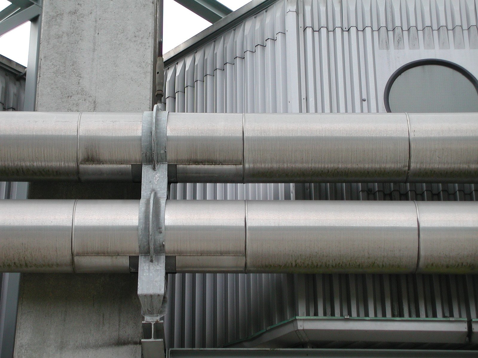 the back side of an industrial building shows metal pipes