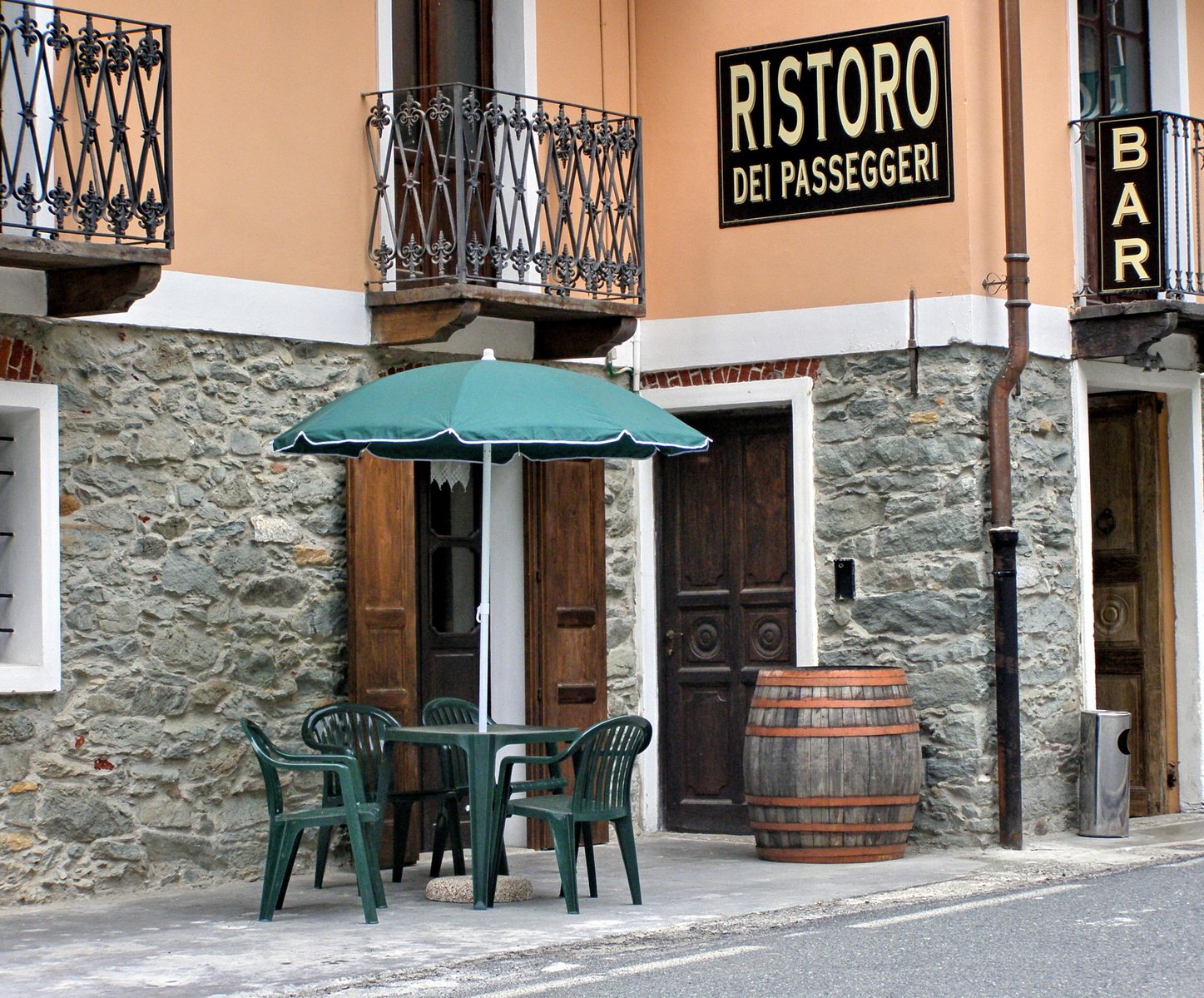 two tables with umbrellas are in front of a small cafe