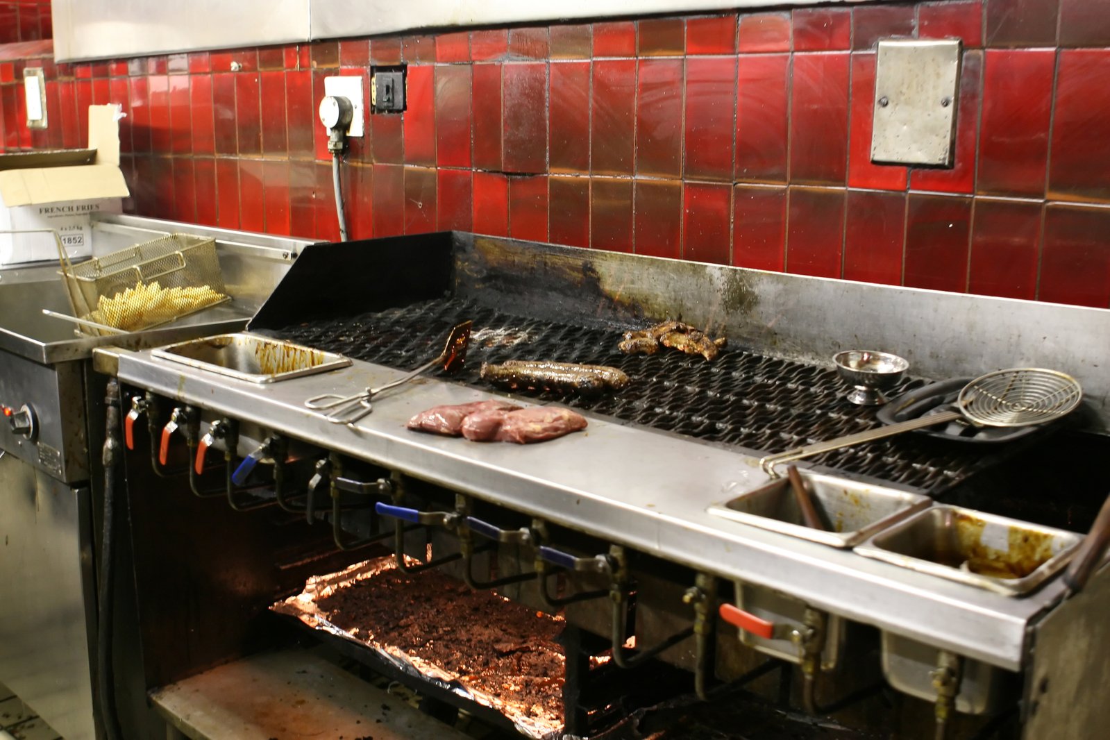 a large grill with food cooking on it next to a sink and counter