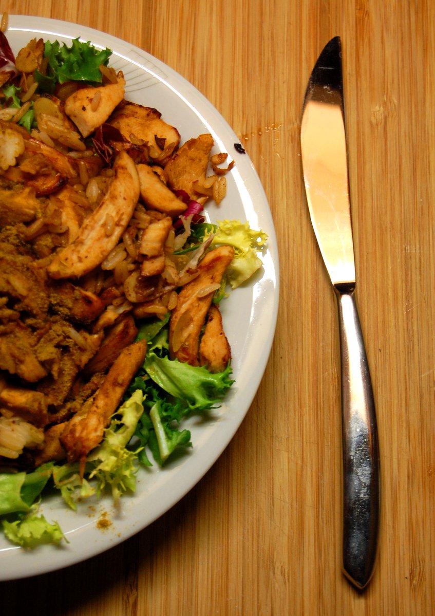 a knife on a wooden table beside a plate of food