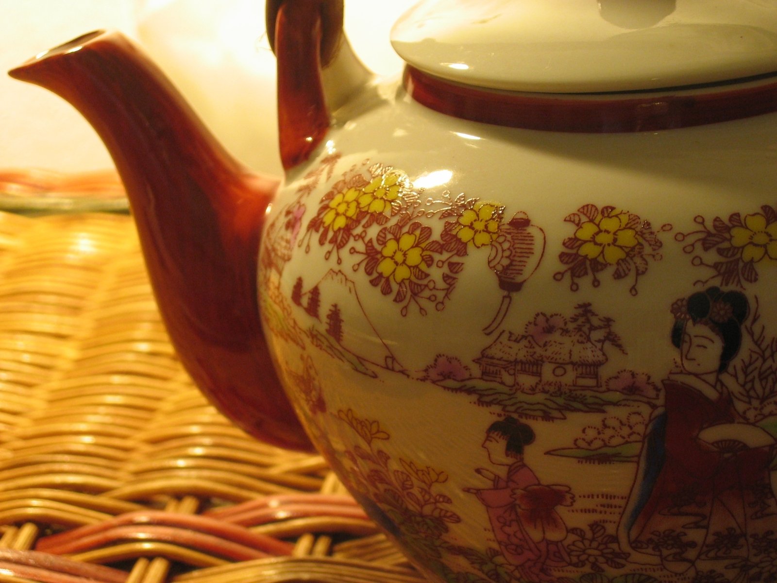 a china style tea pot sitting on top of a woven basket