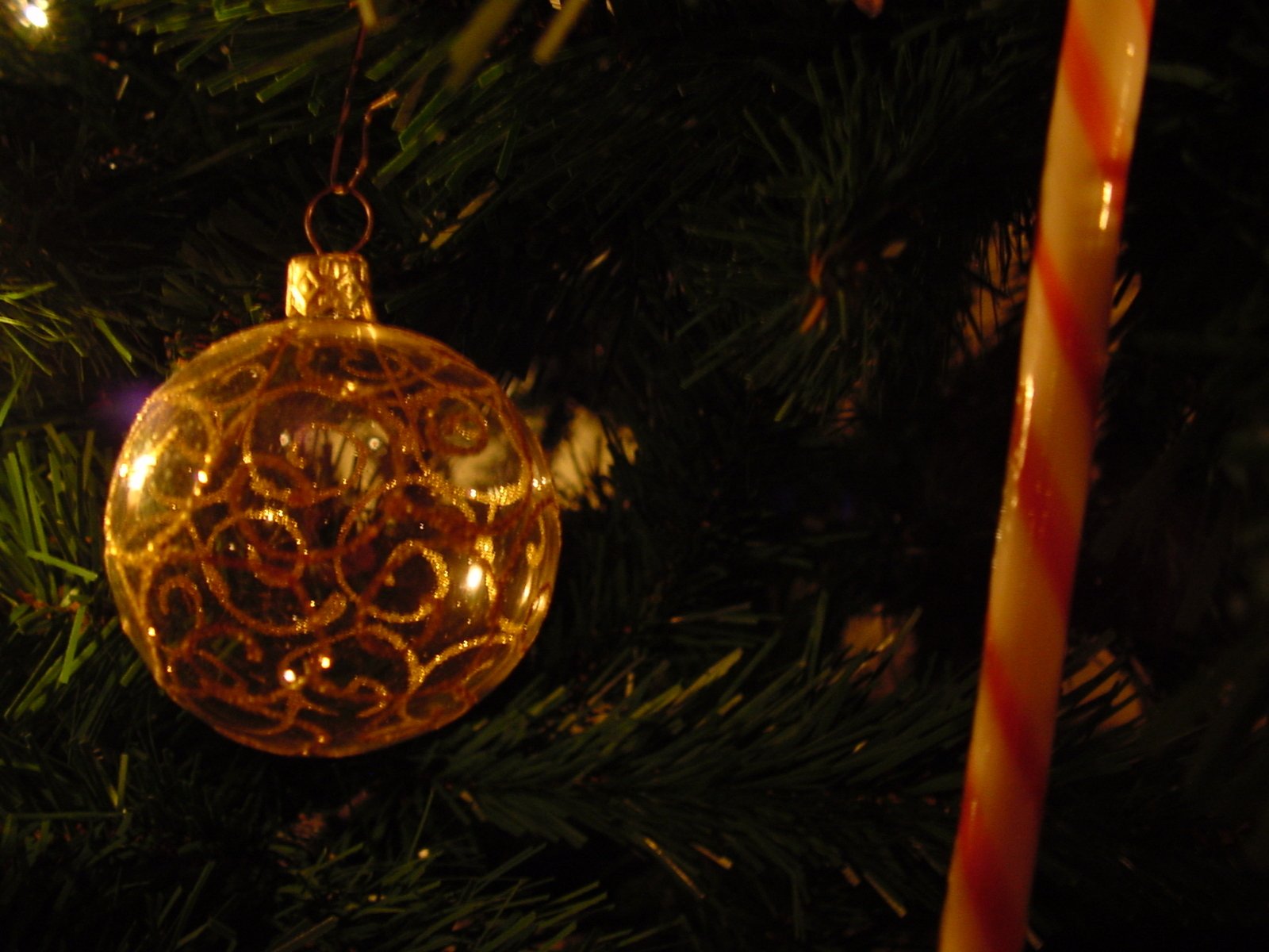 a shiny yellow christmas ornament hanging from a christmas tree