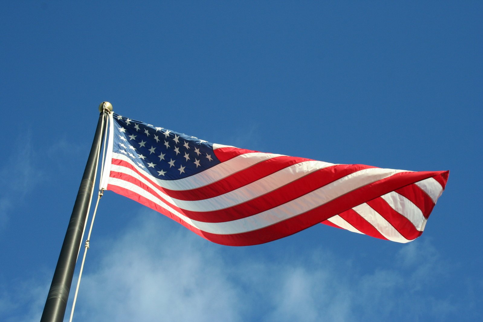 a large american flag flying in a blue sky