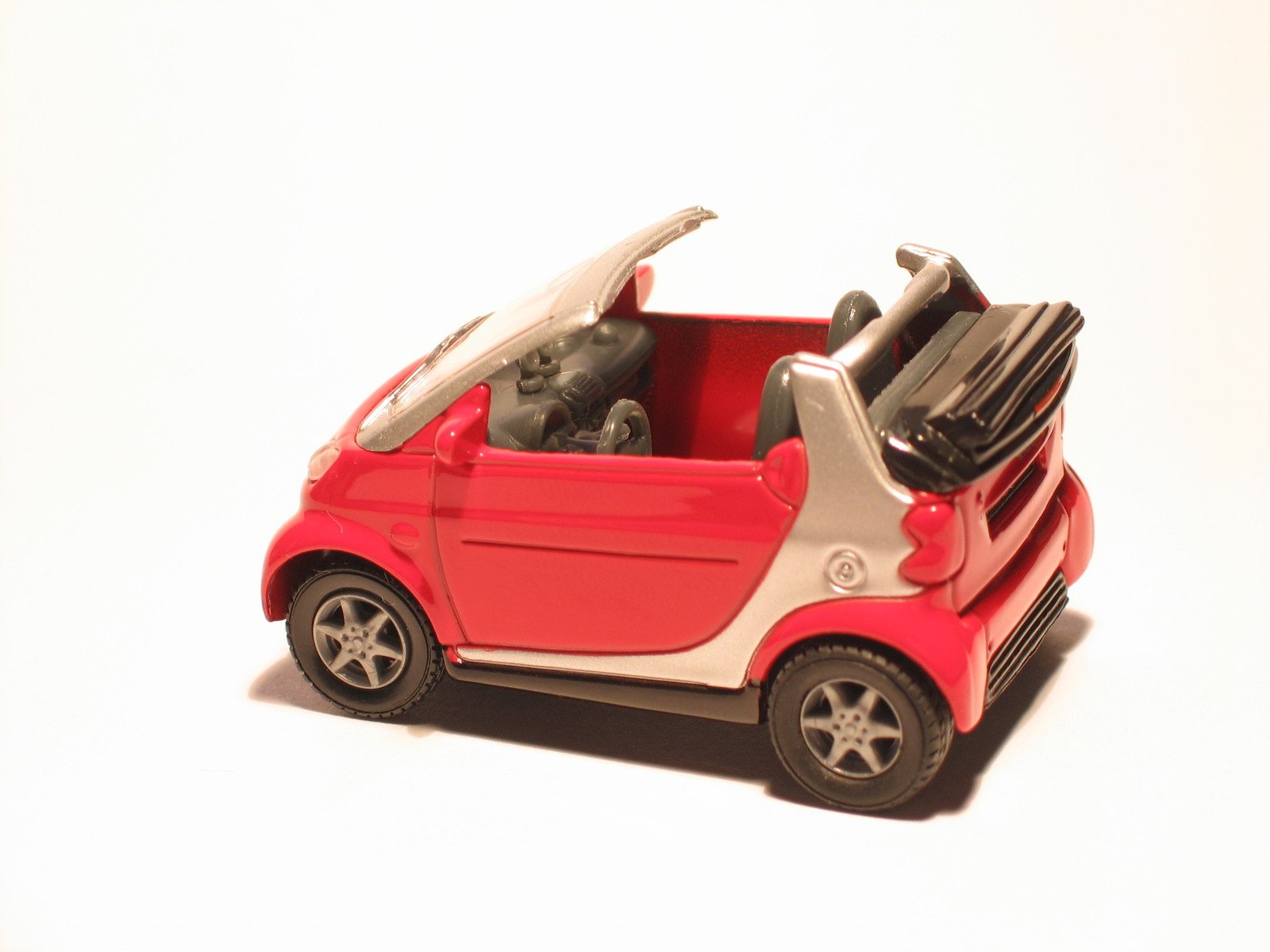 a small red toy car on white surface