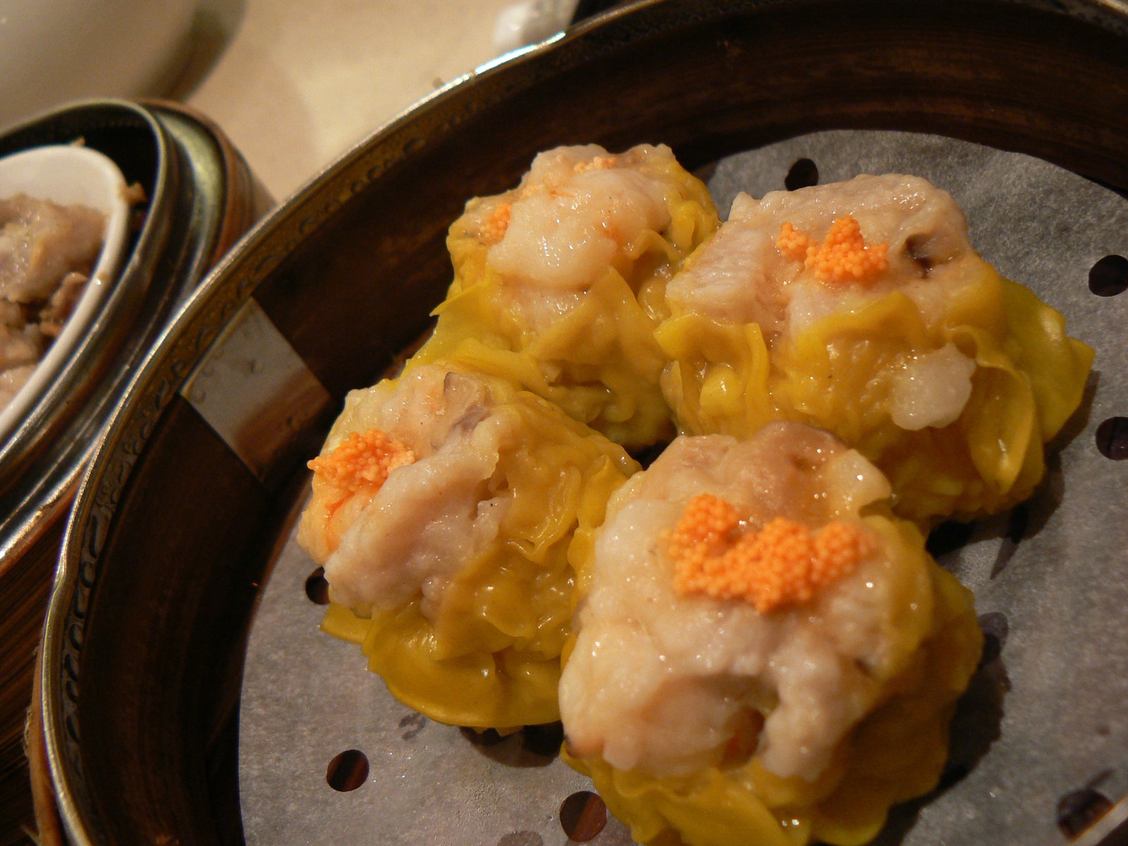 some food is sitting in an asian steamer with one of the dishes being eaten