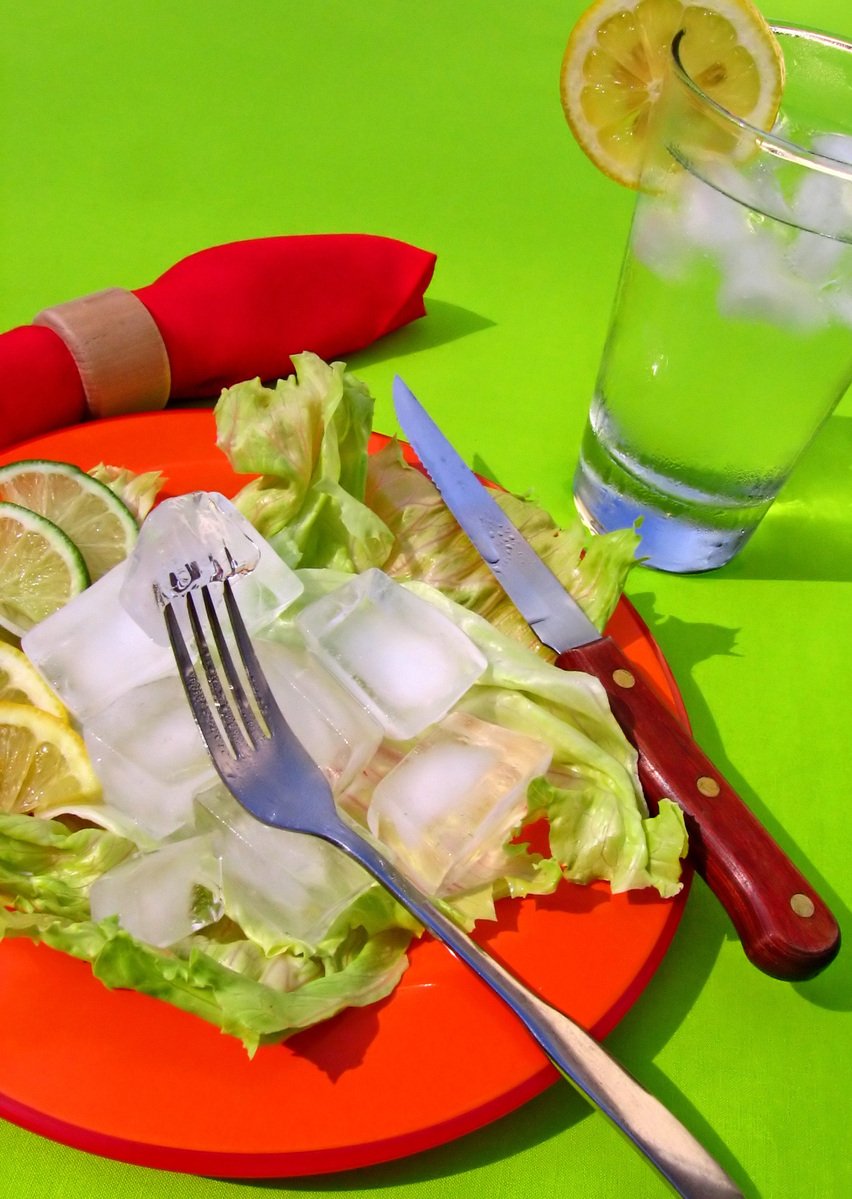 a plate with a salad, lemon wedges and silverware on it