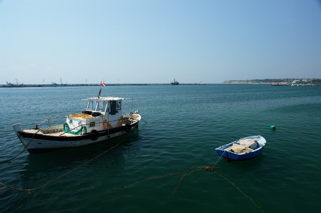 two boats sitting in the water with ropes