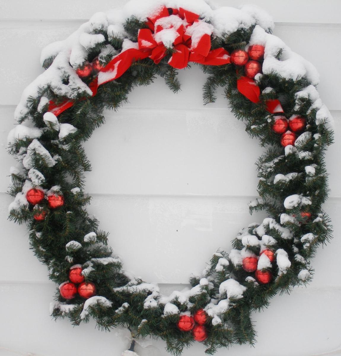 a snow covered wreath that has ornaments on it