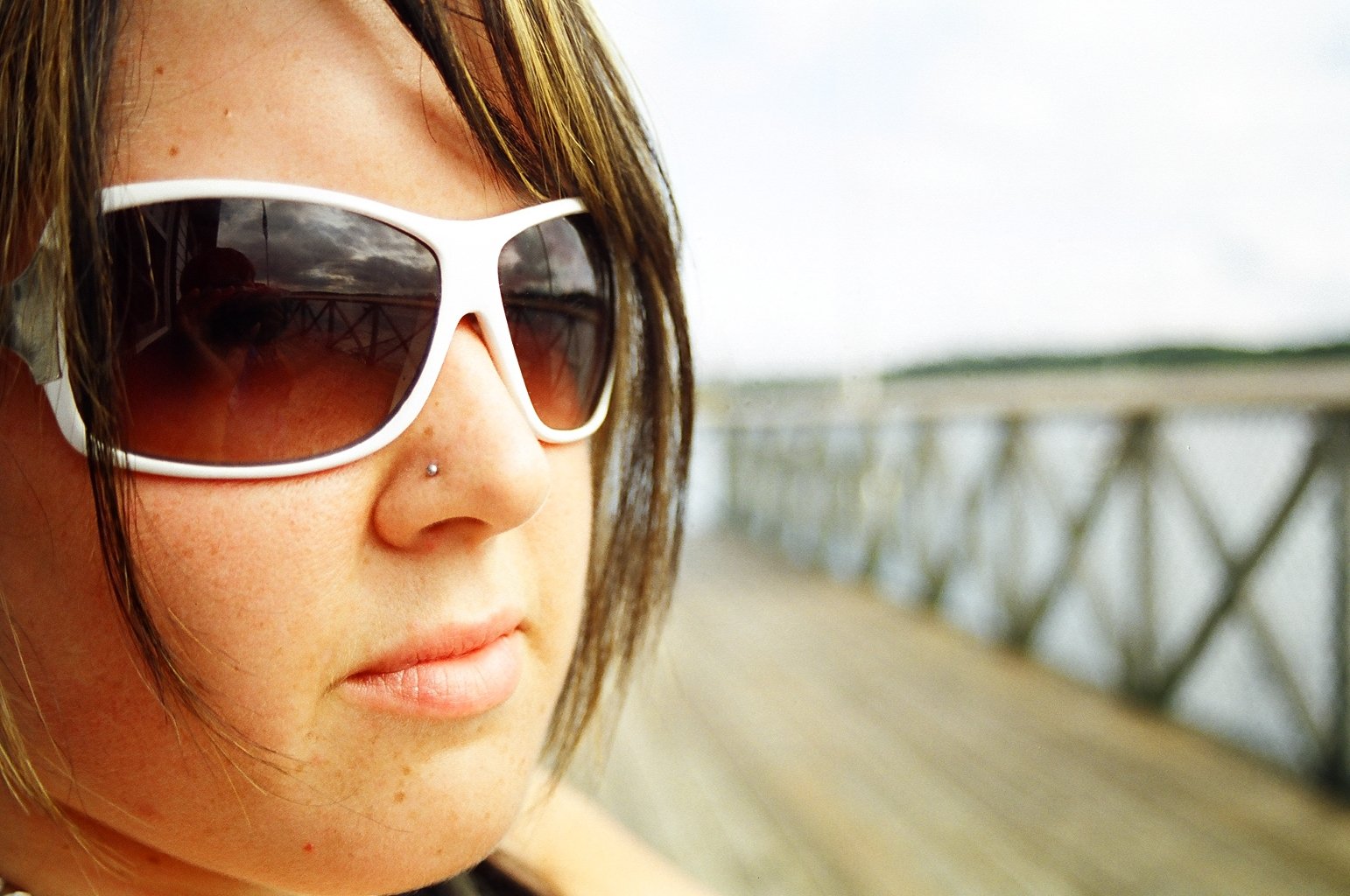 a woman in shades is near the edge of a pier