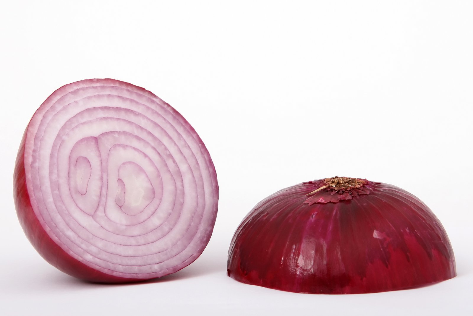 a peeled red onion is near an onion slice
