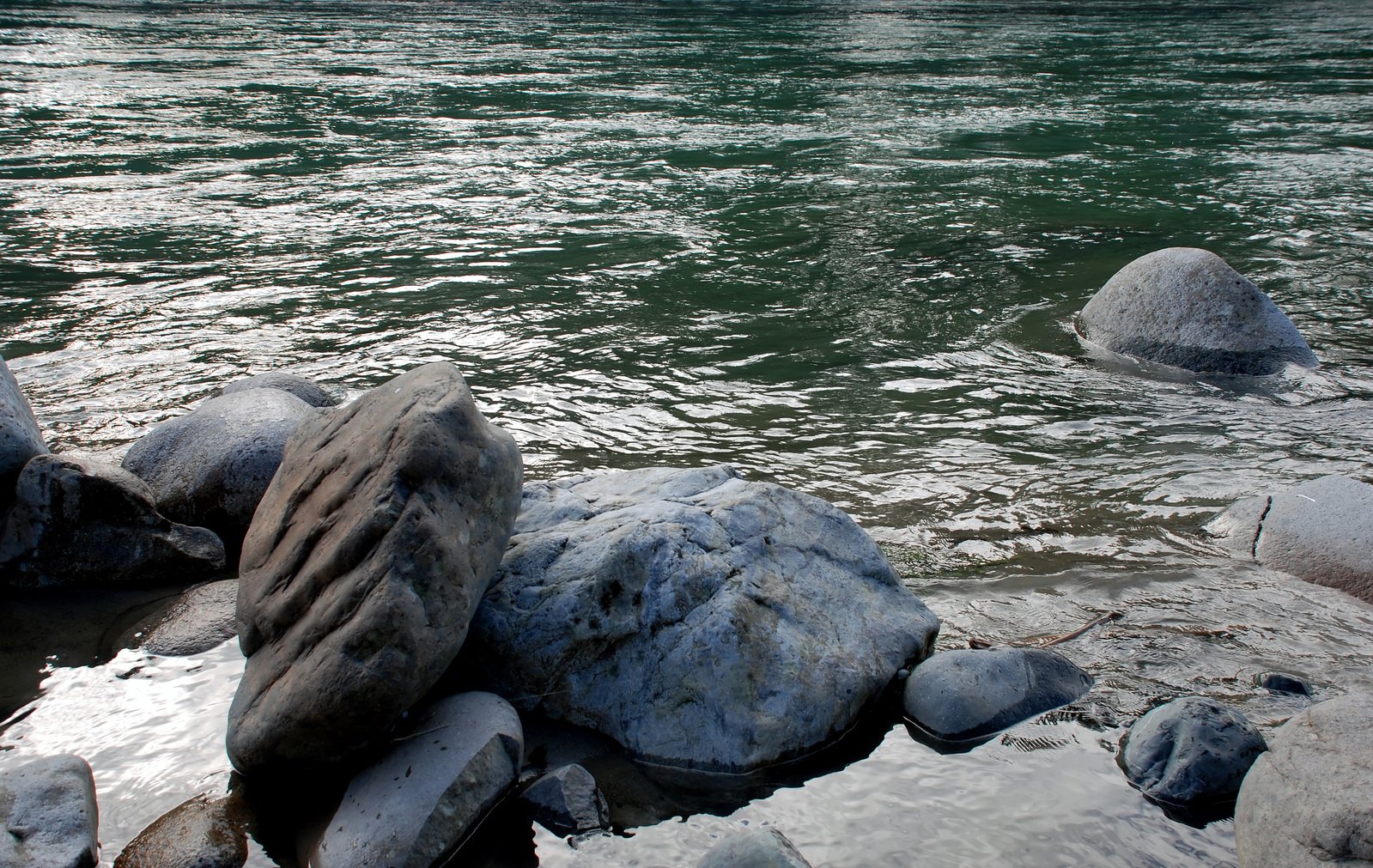 a bench and a rock near the ocean