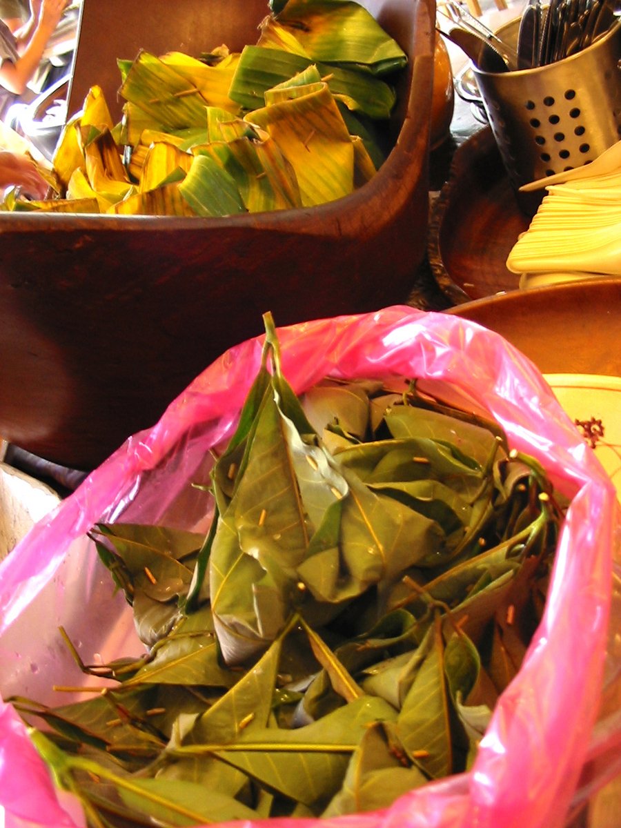 a bag of leaves on a table next to a wooden bowl with other items in the background