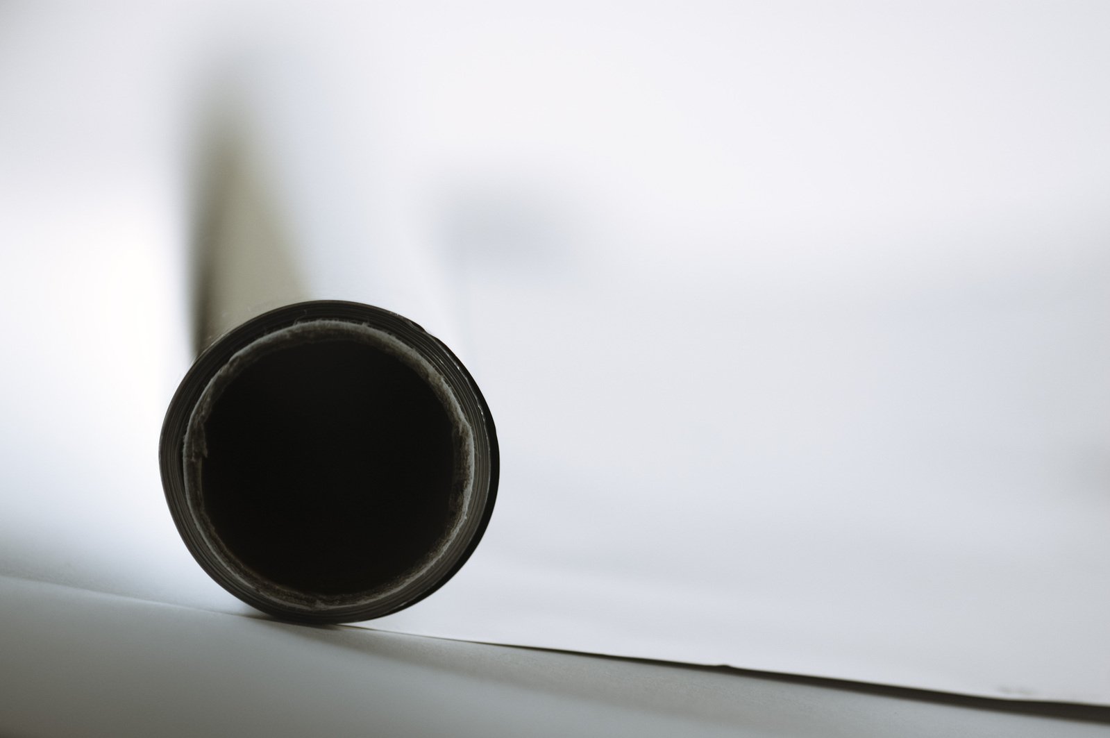 a black tube leaning towards the right with a white backdrop