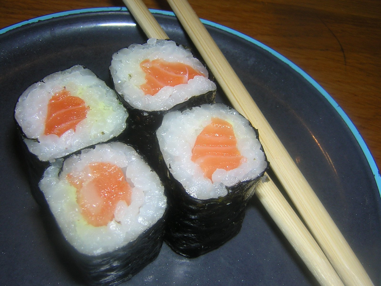 a small plate holding rolls with sushi, chopsticks