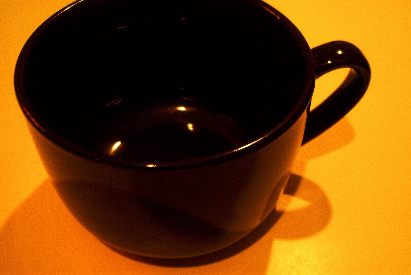 a dark colored coffee cup sitting on top of a yellow table