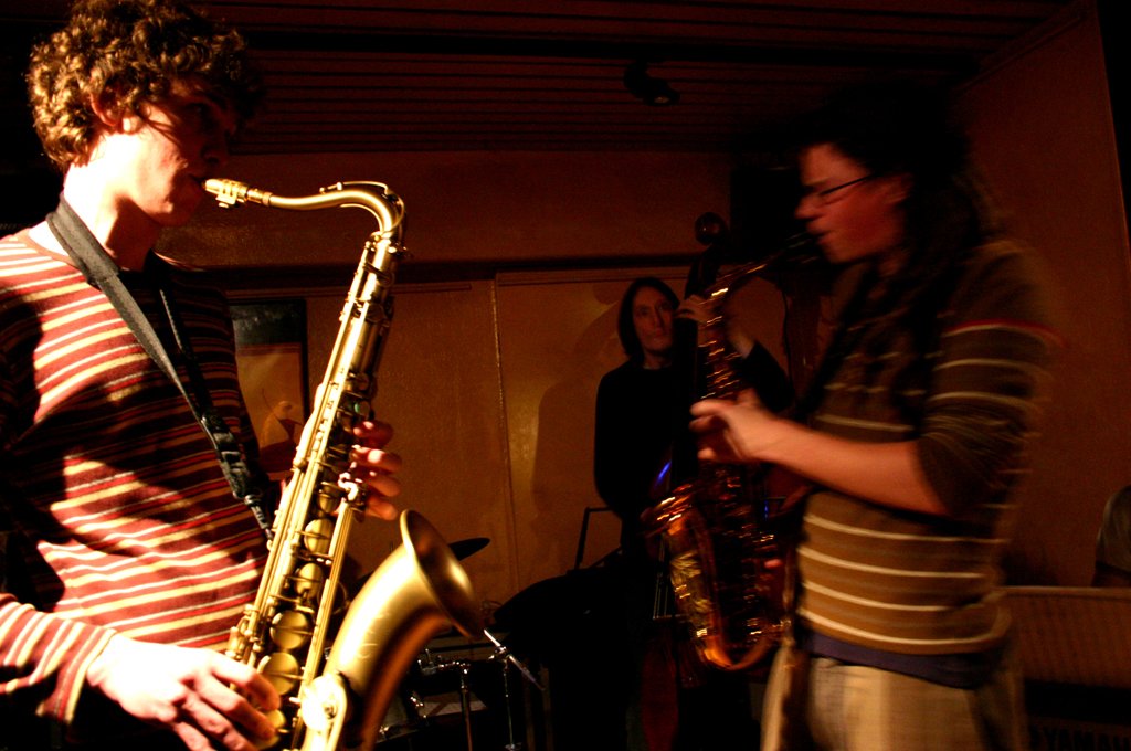 two men standing in front of a saxophone