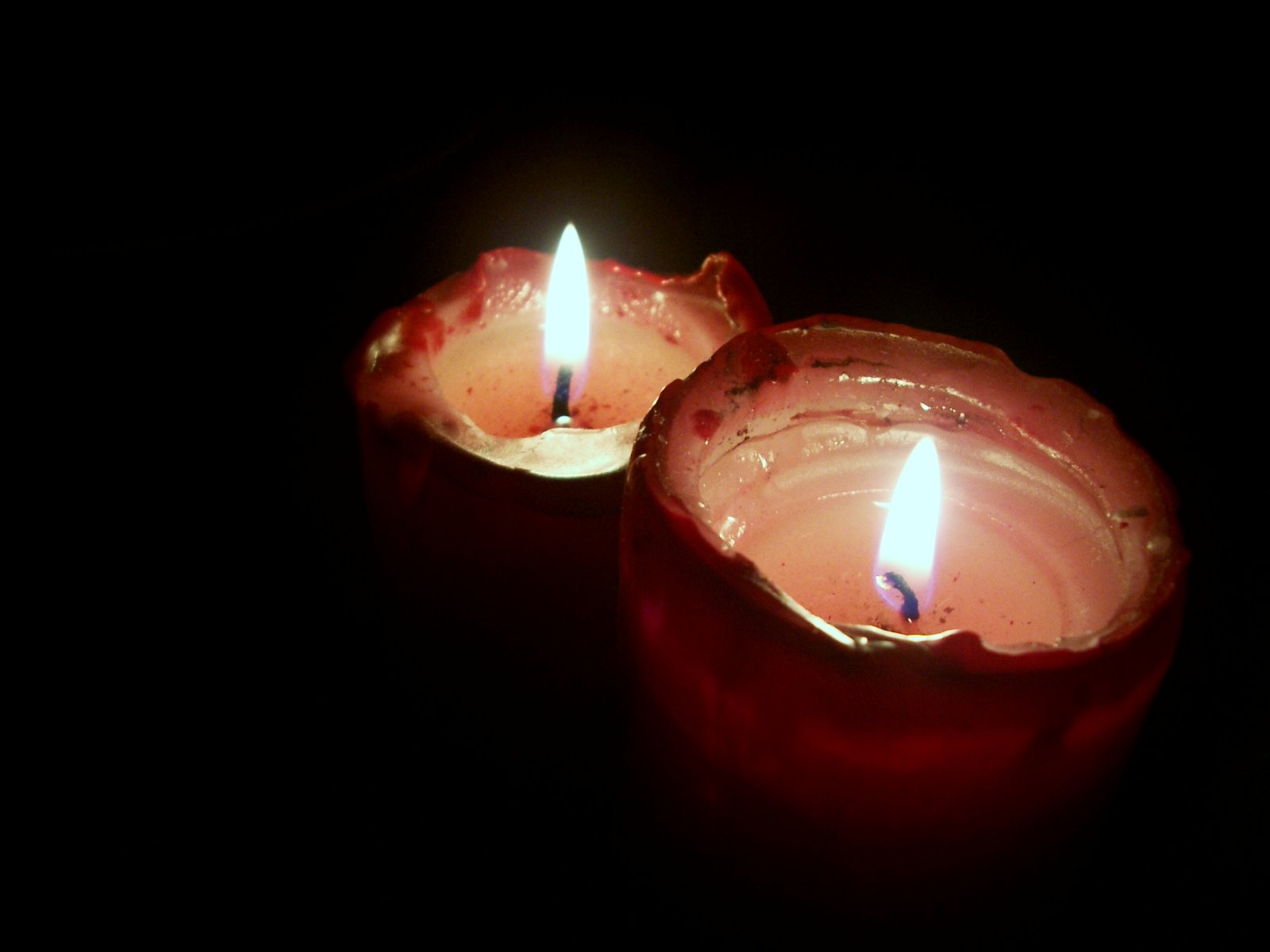 two lit candles with a dark background