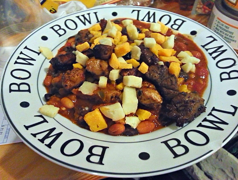 a bowl full of stew and a bottle of booze on the side