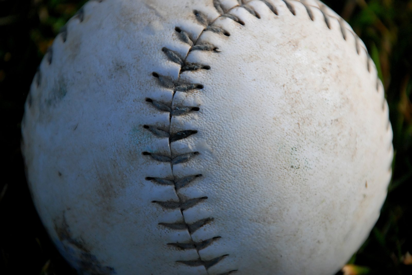 an old baseball laying on a grass covered field