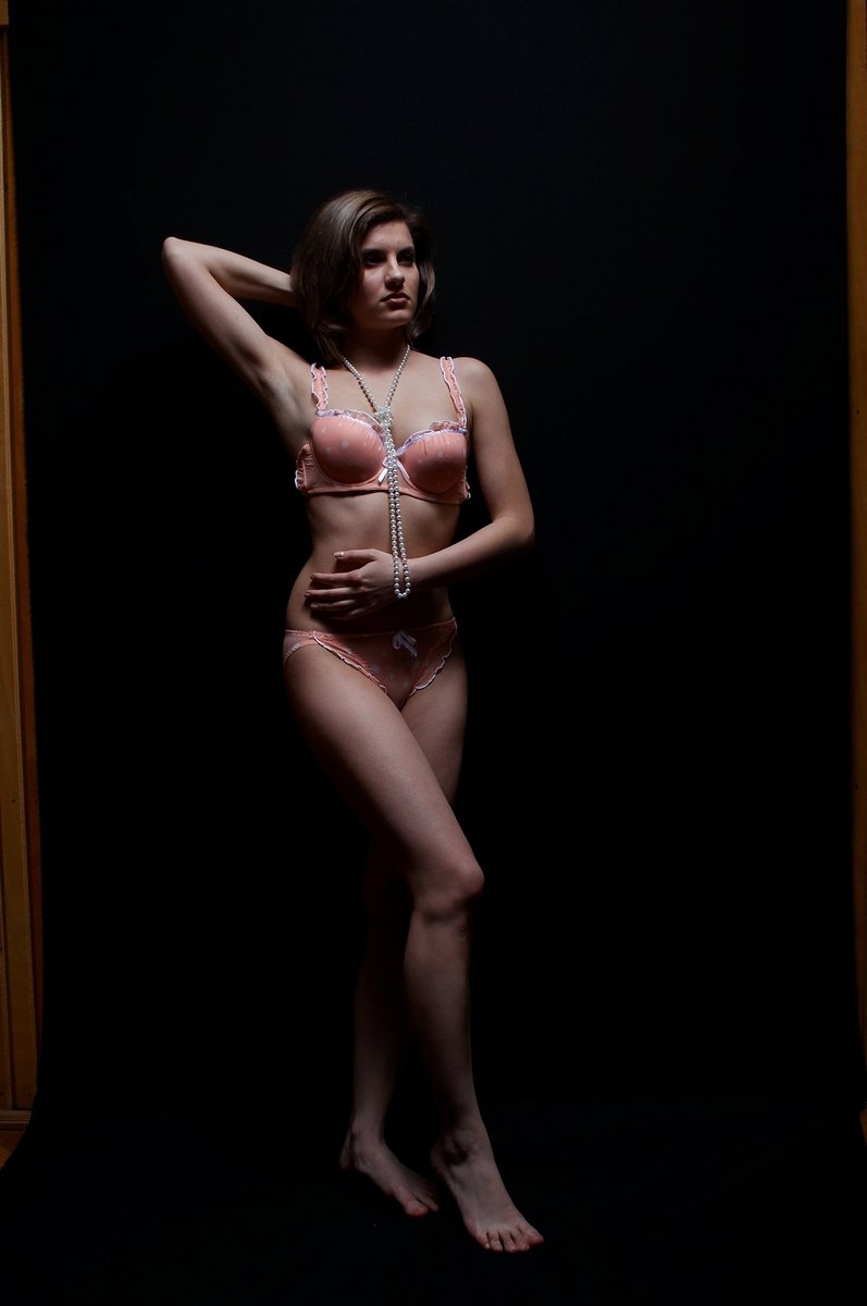 a beautiful young lady in her underwear posing in a dark room