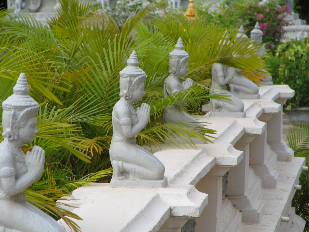 some little statues sitting on a ledge by a plant