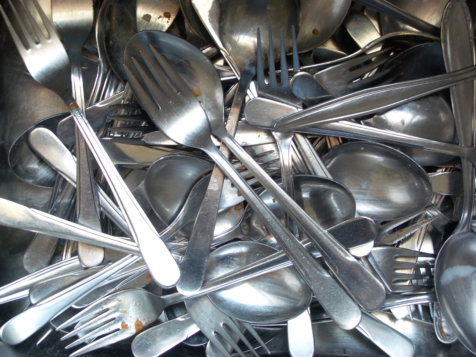 a pile of shiny silverware with different types of spoons