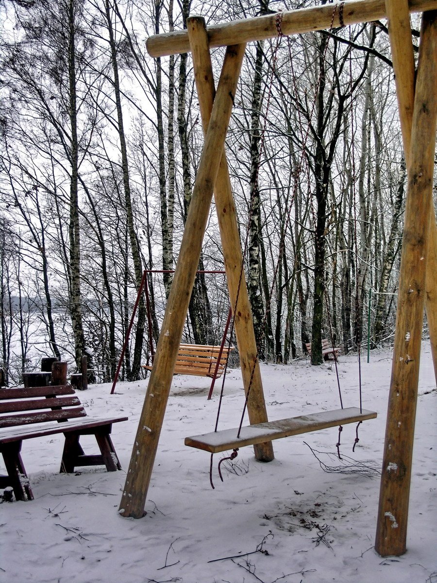 two swing chairs and a bench in the snow