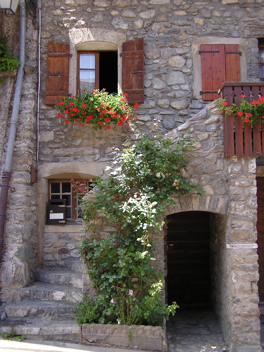 a house that is brick with some flowers in the windows