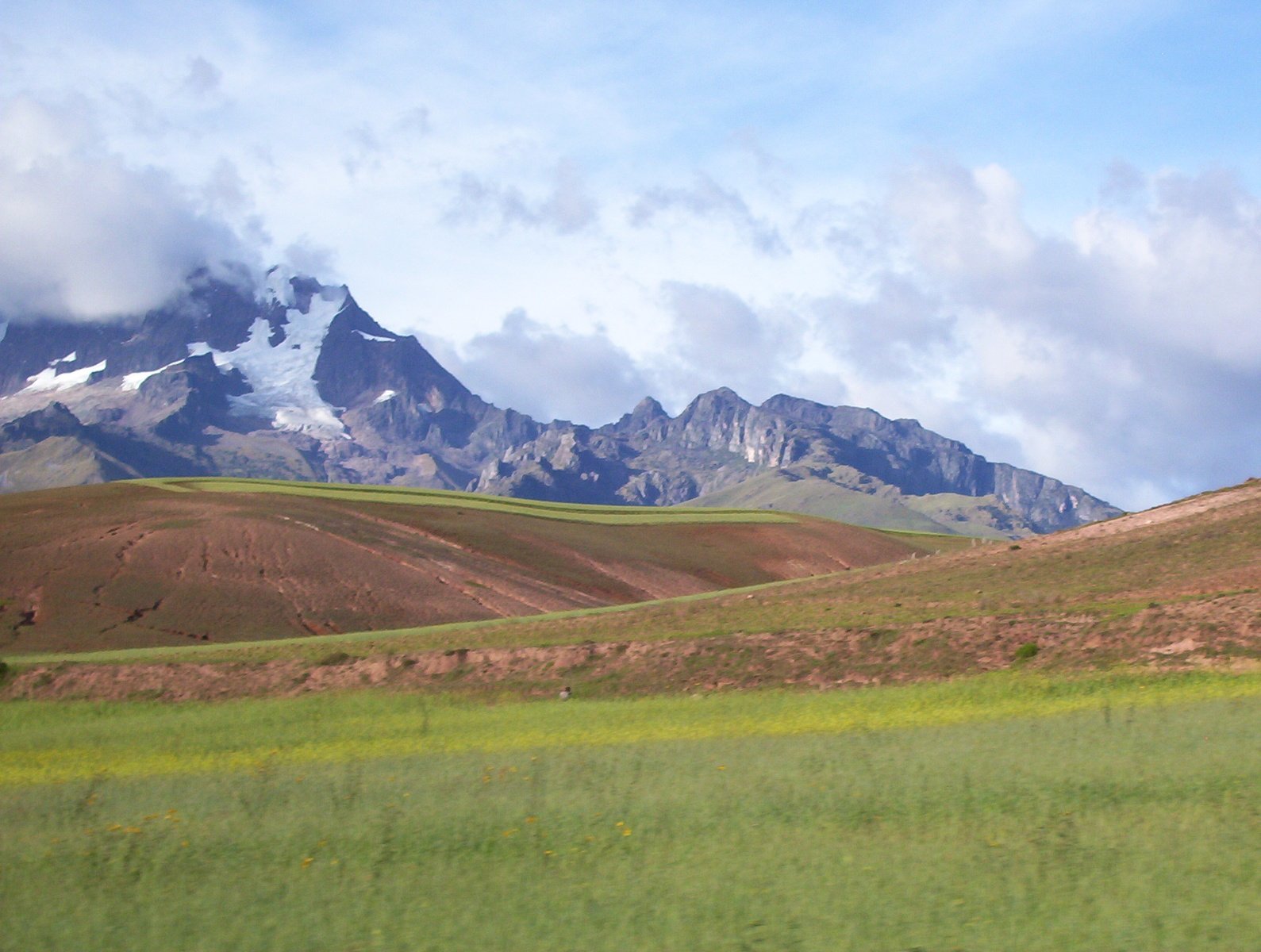 the mountains are surrounded by grassy plain and sky