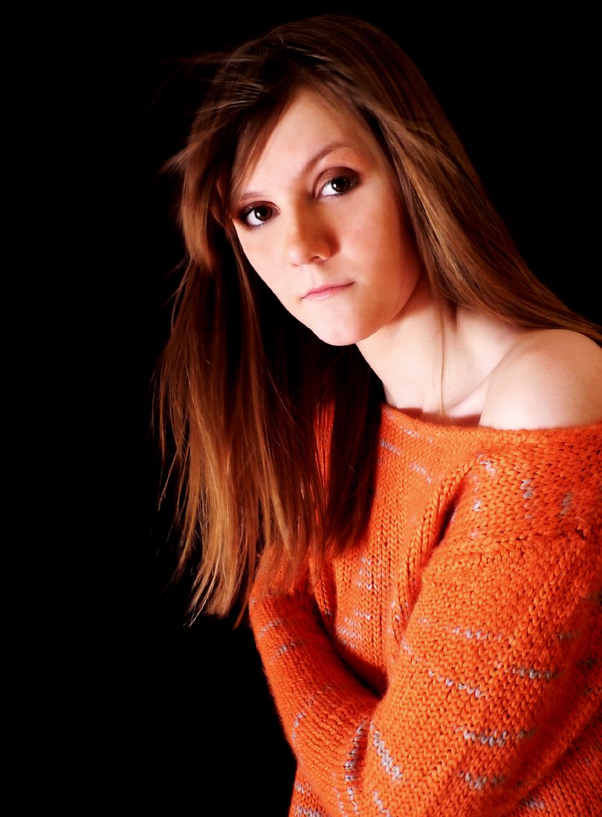 a girl with long hair wearing an orange sweater