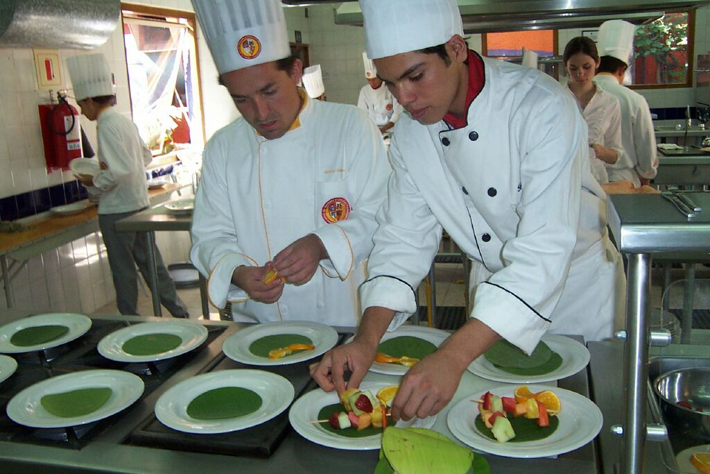 two chefs preparing food inside of a kitchen