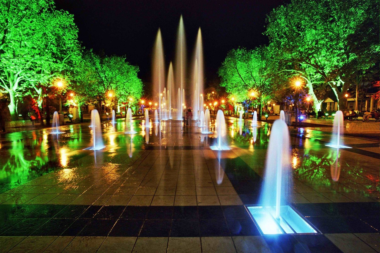 fountains in an open space with trees on either side