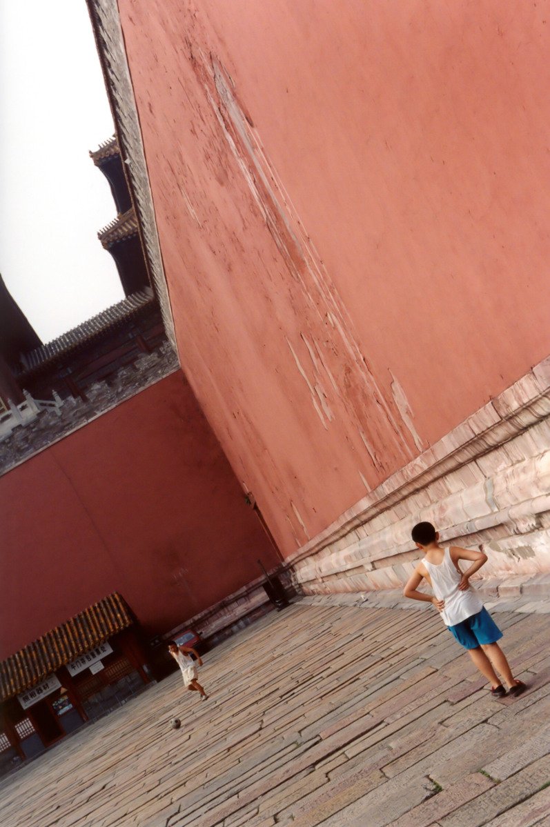 two boys standing near a building with benches