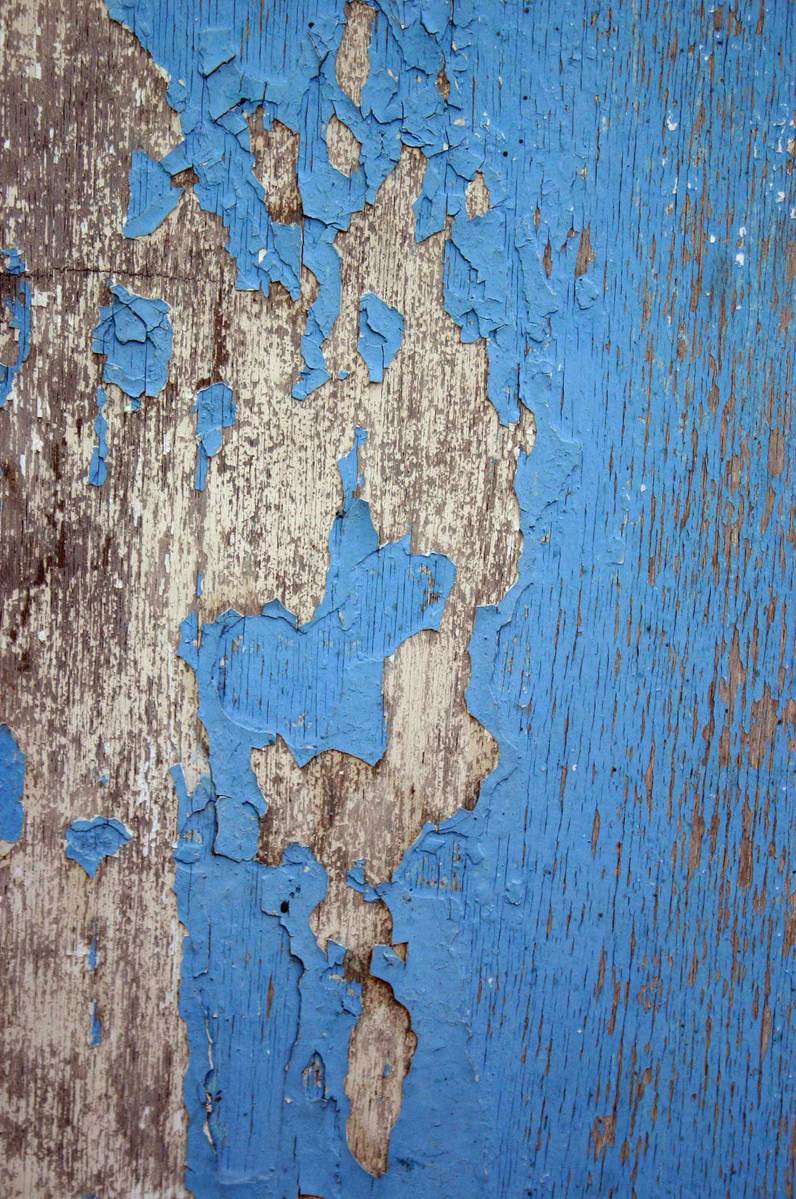 closeup of paint peeling off a wall, fading blue