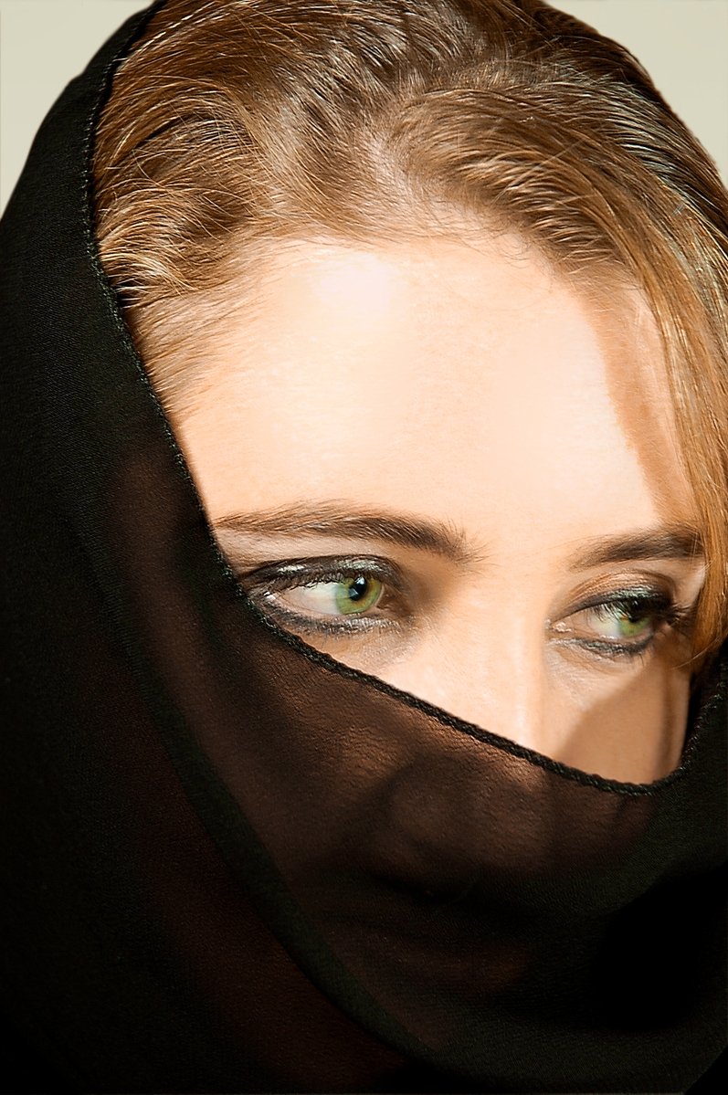 a young woman's green eyes are reflected in a veil