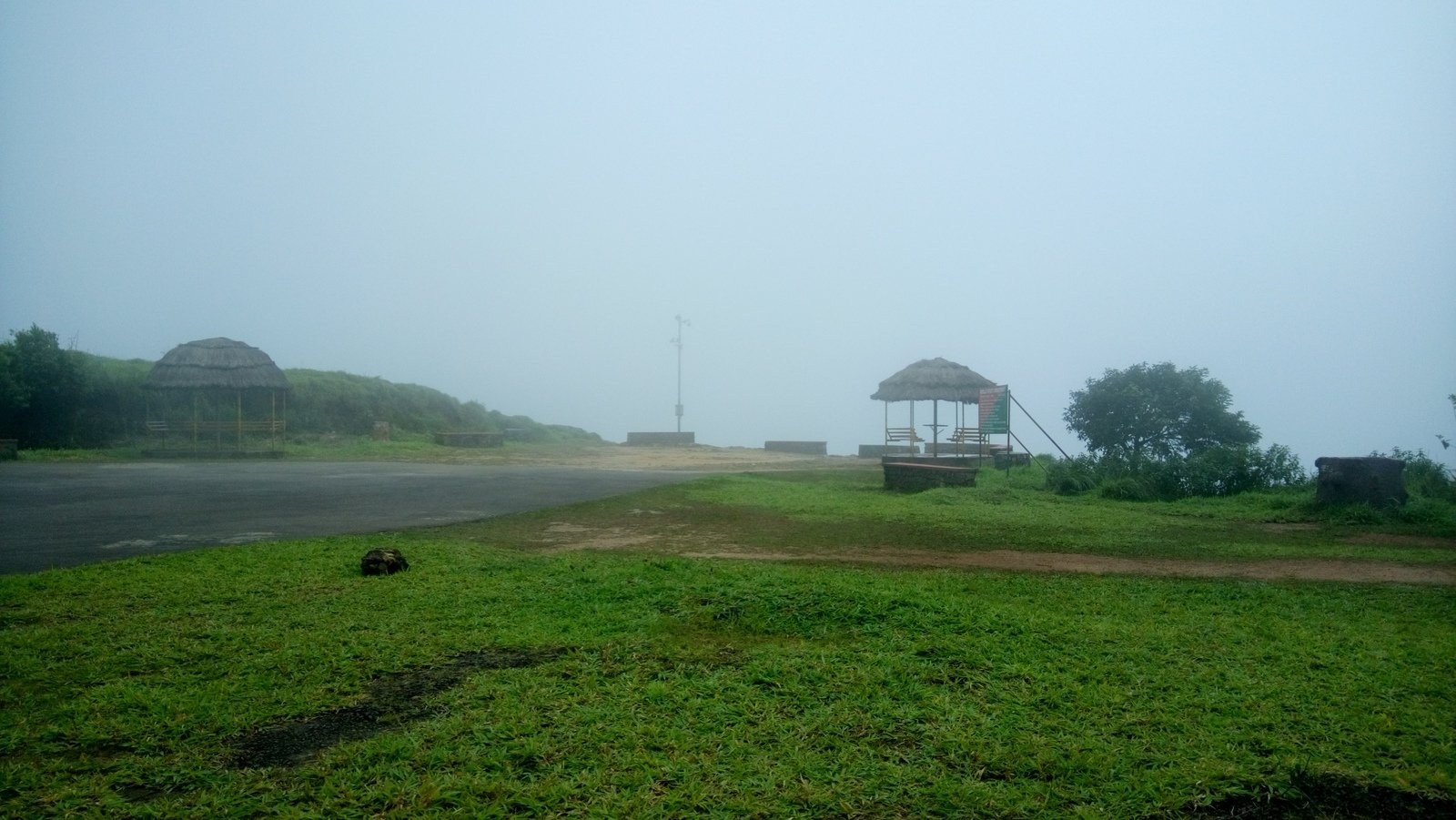 a foggy and grassy area with benches, and huts