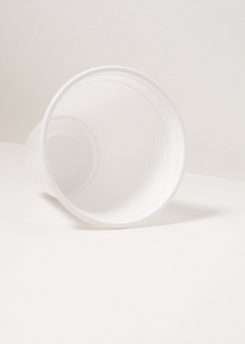 a white cup with a spiral design is sitting on a white table