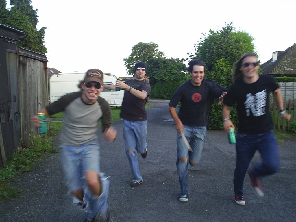 four young men running down a street together