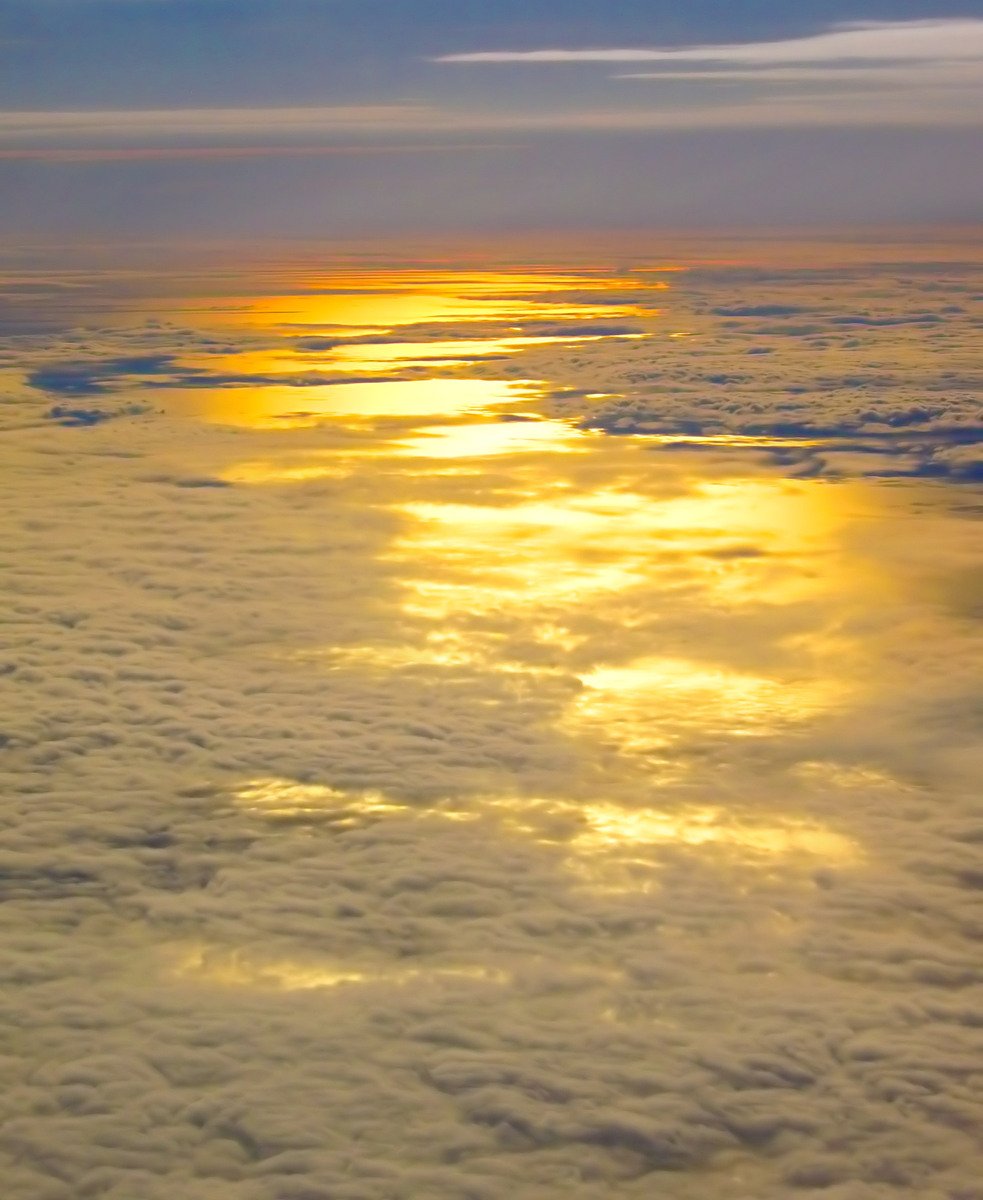 the sun setting over some clouds below