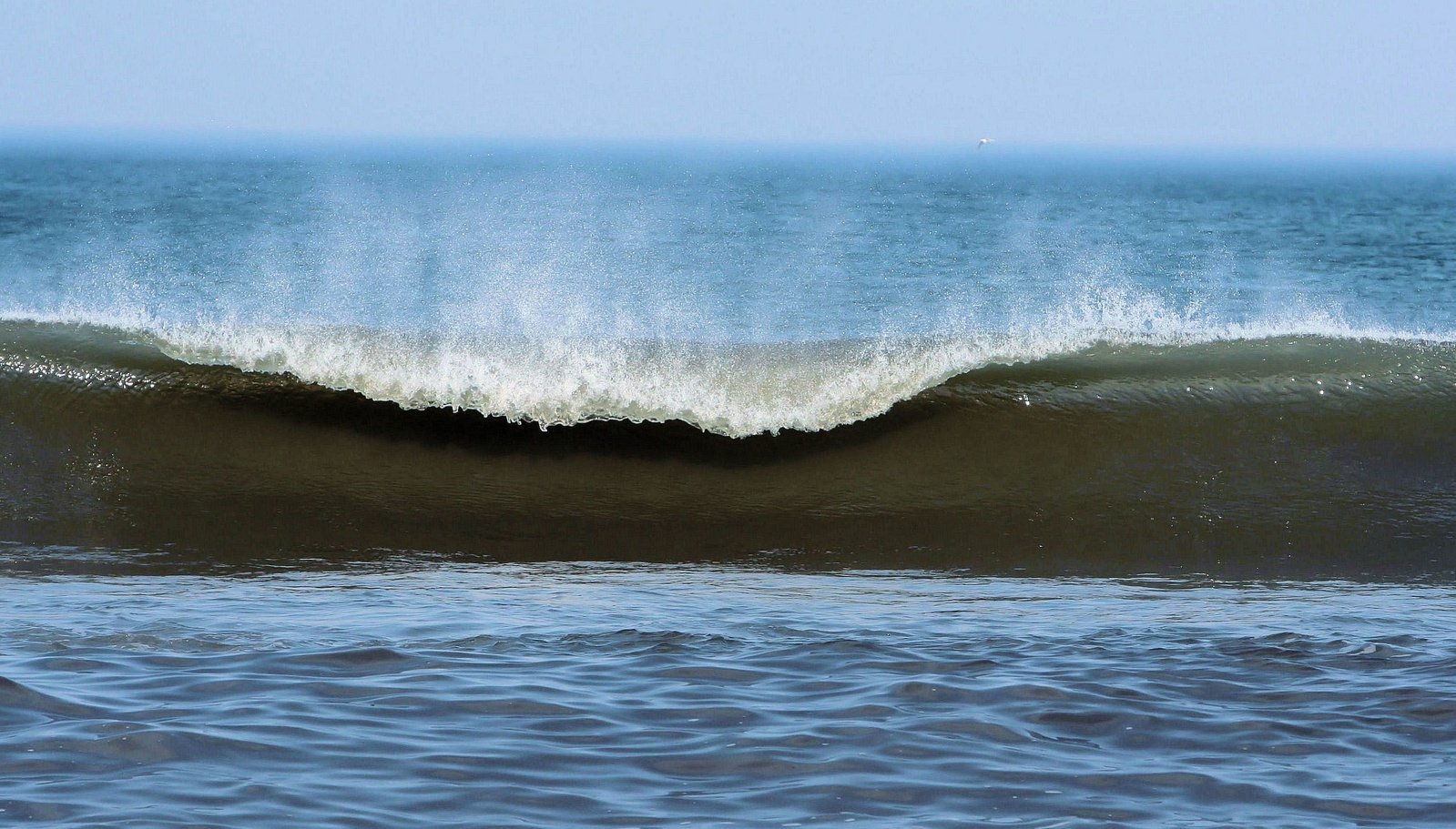 an ocean wave is crashing at the beach