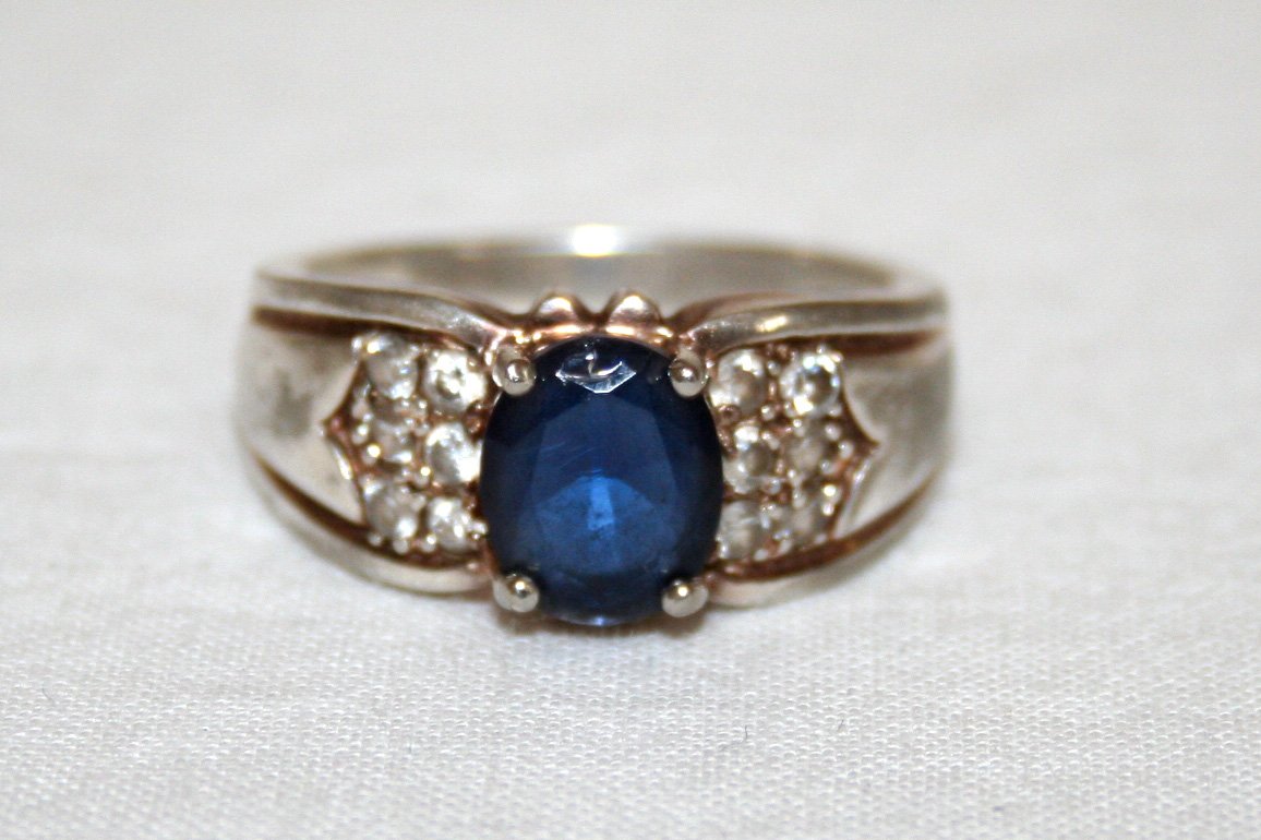 a wedding ring with a blue and white sapphire surrounded by two smaller diamonds