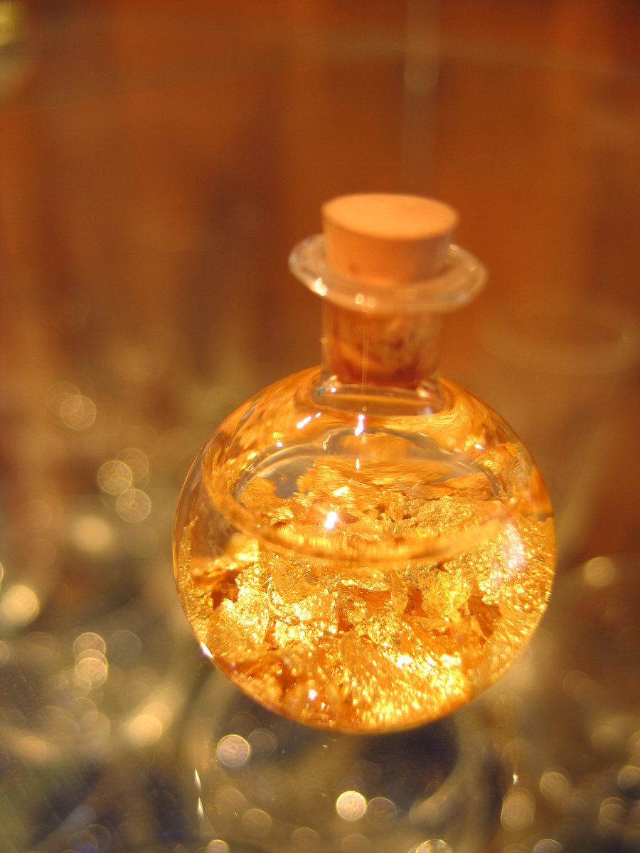 a glass object filled with some liquid and gold flakes