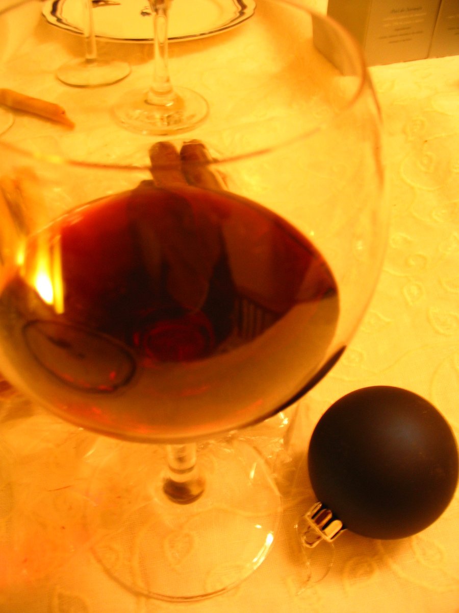 a close up of a wine glass with red liquid and two items