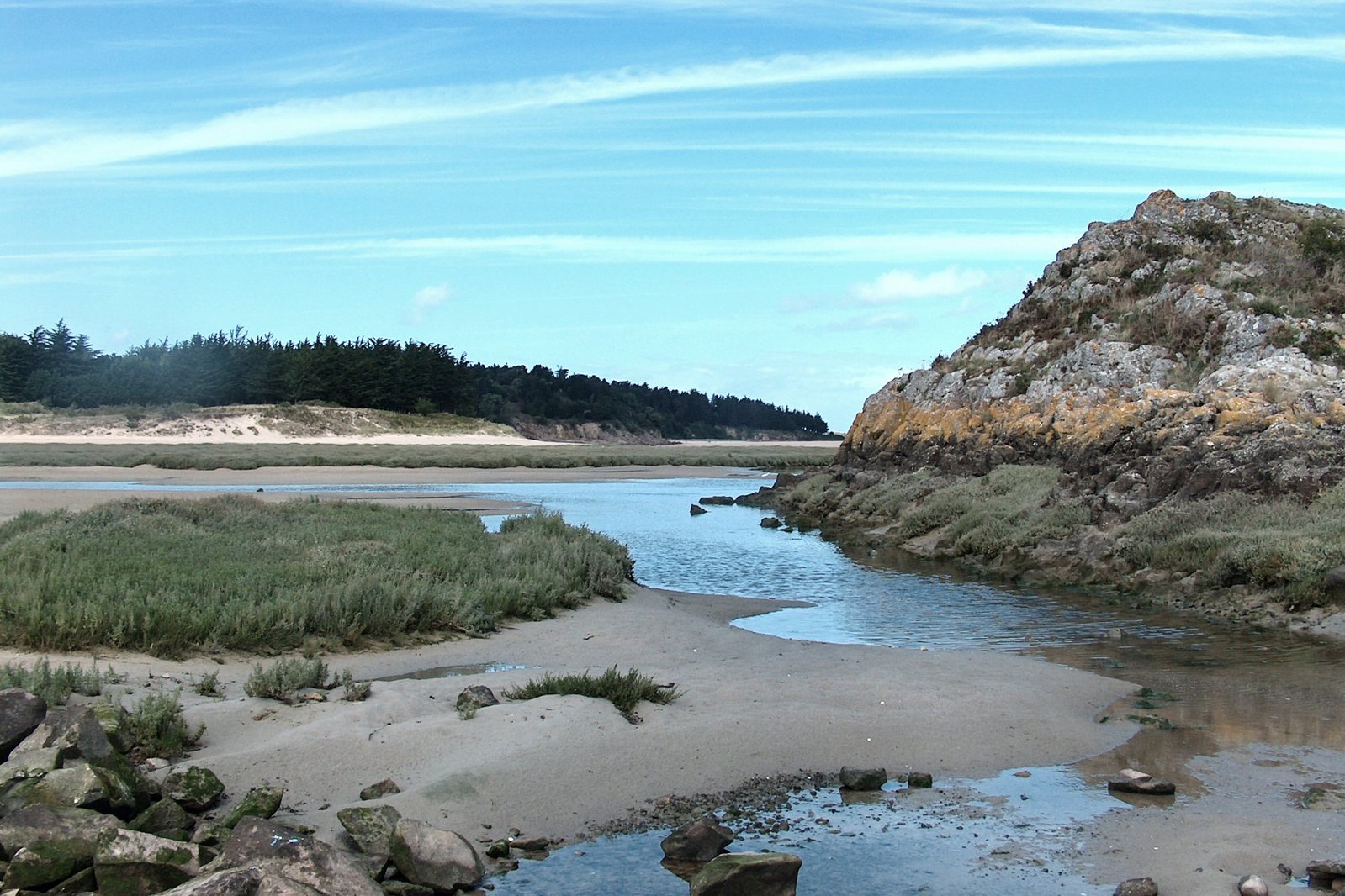 a rocky outcropping on the beach next to a river