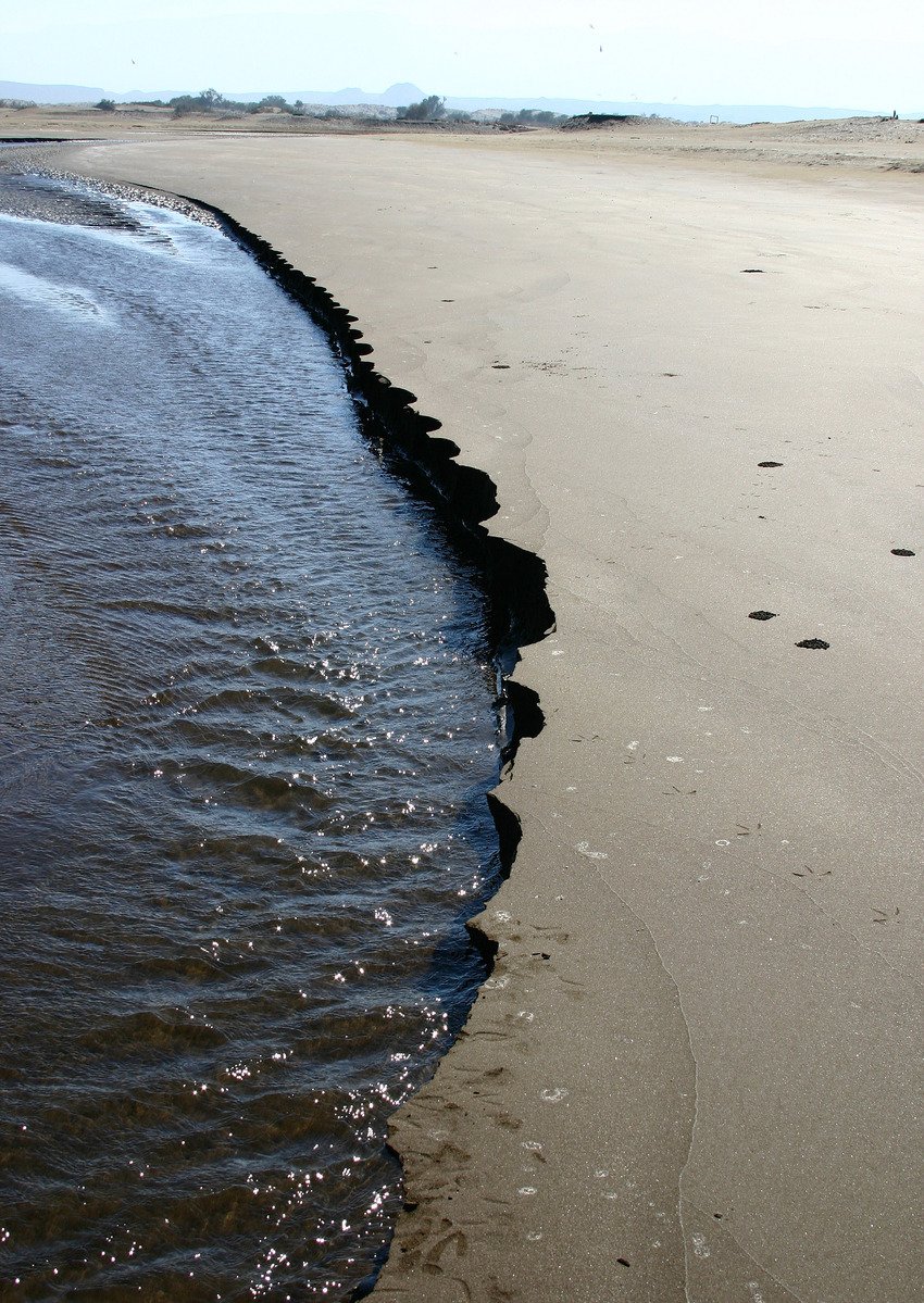 water flows on the edge of a beach as it passes