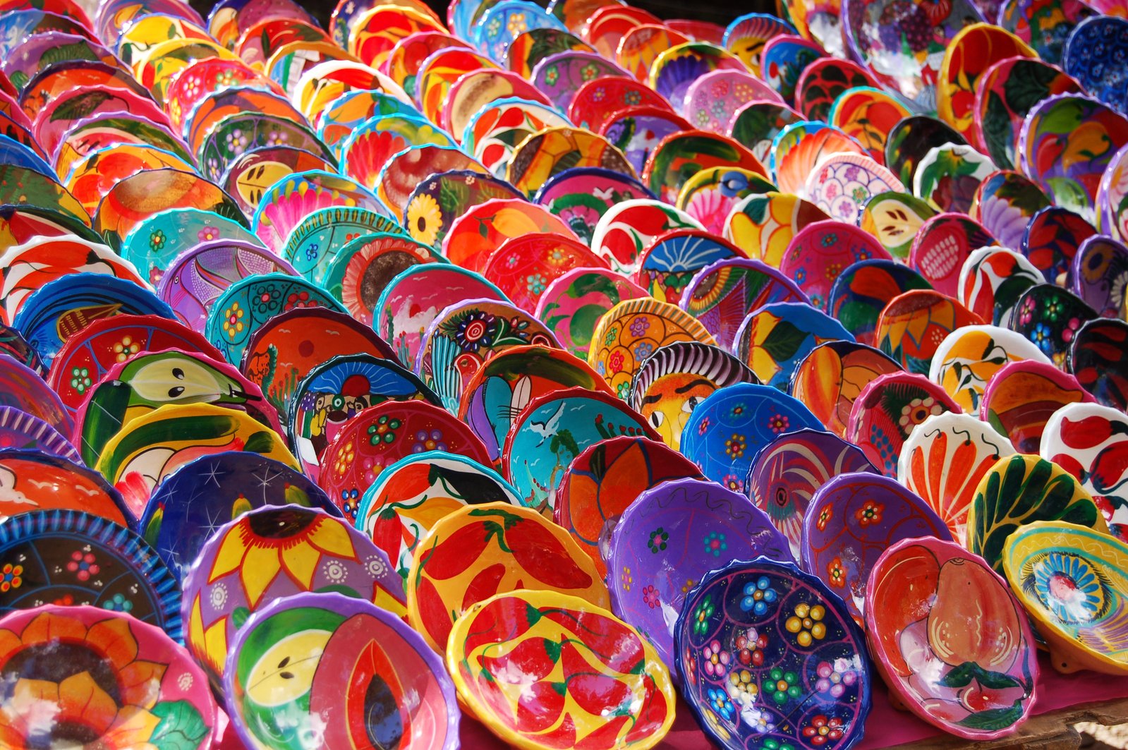 colorful plates are laid out in rows for sale