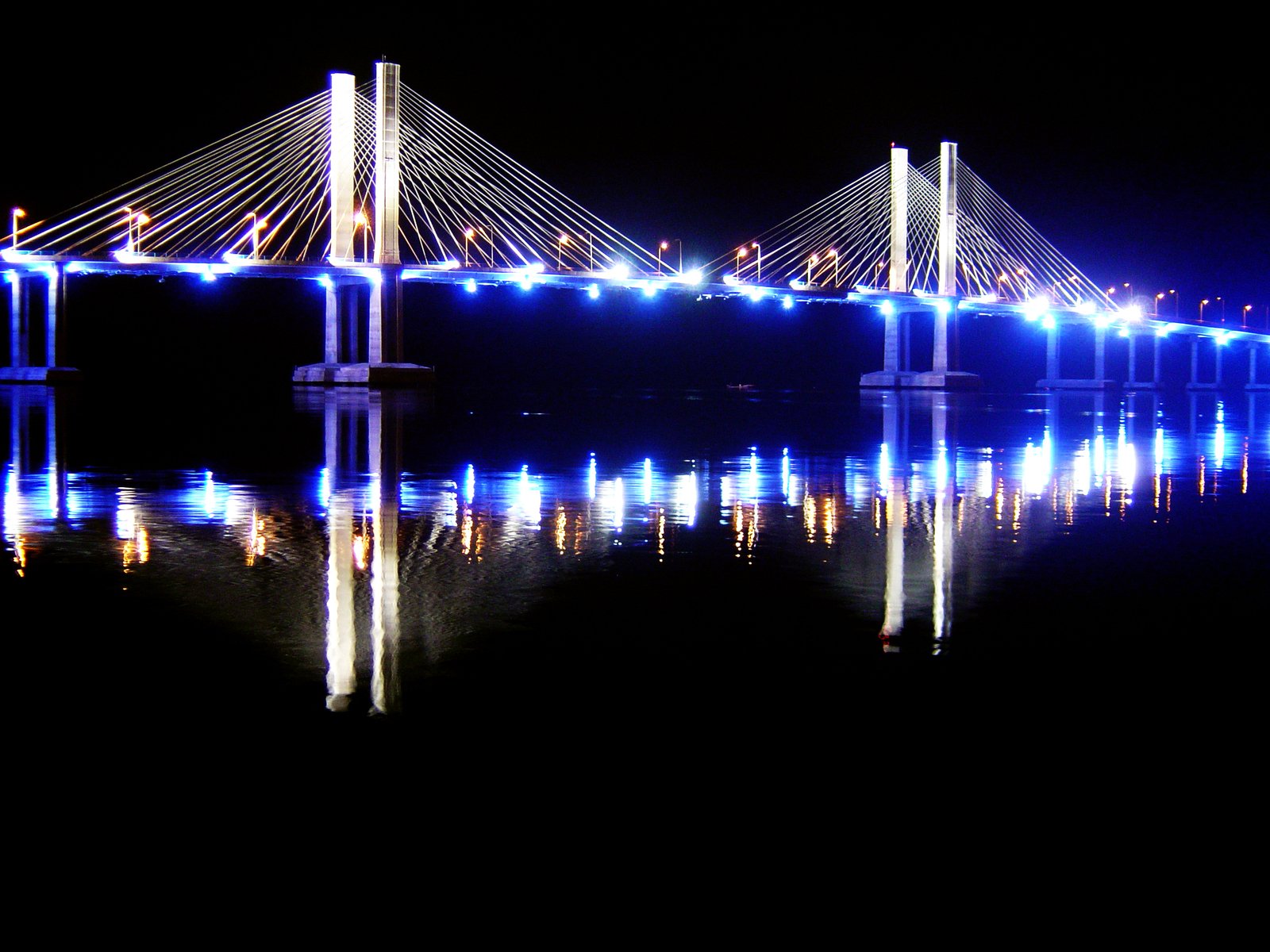 a long bridge spans over the water at night