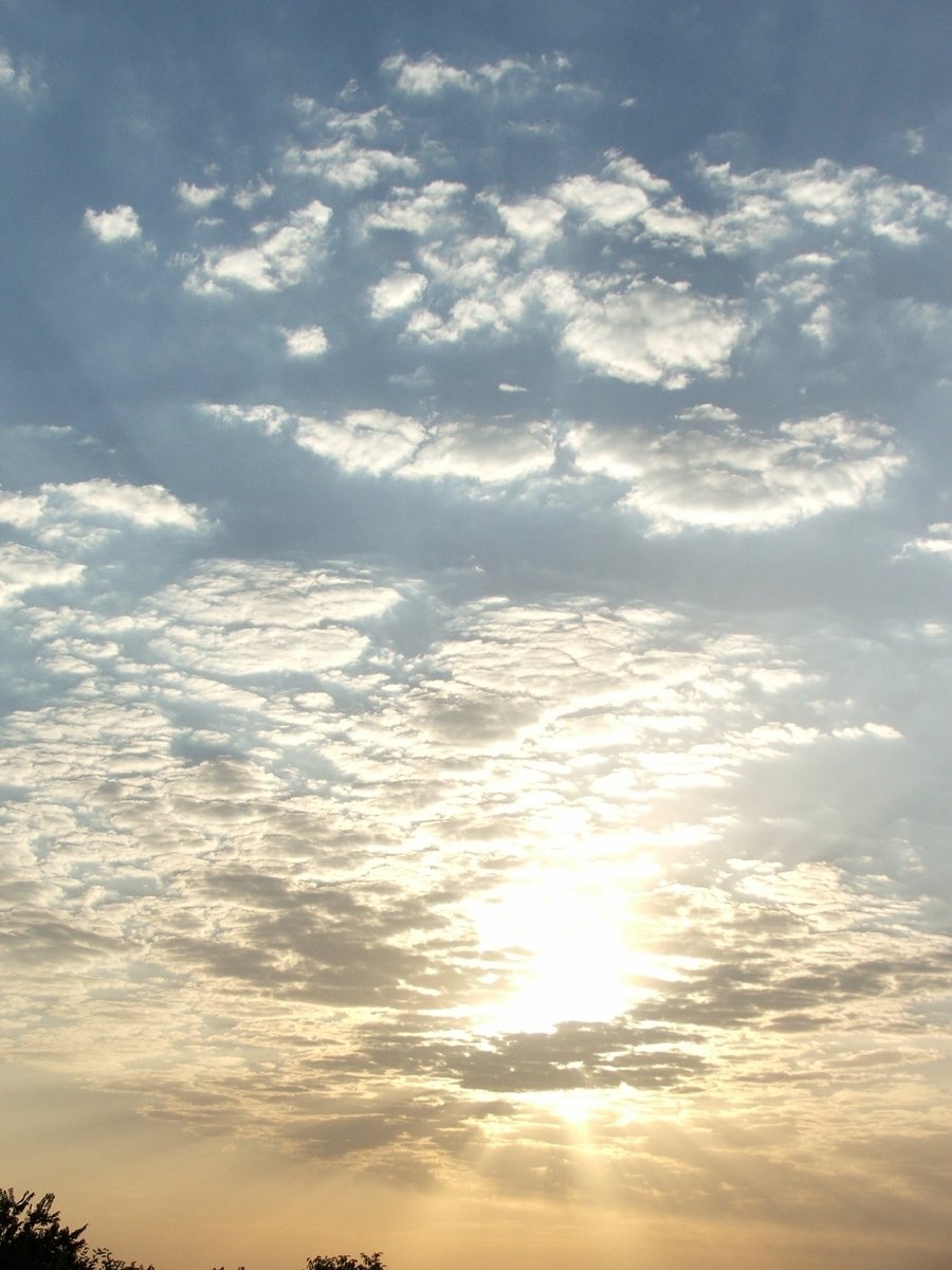 the setting sun behind clouds in a sky